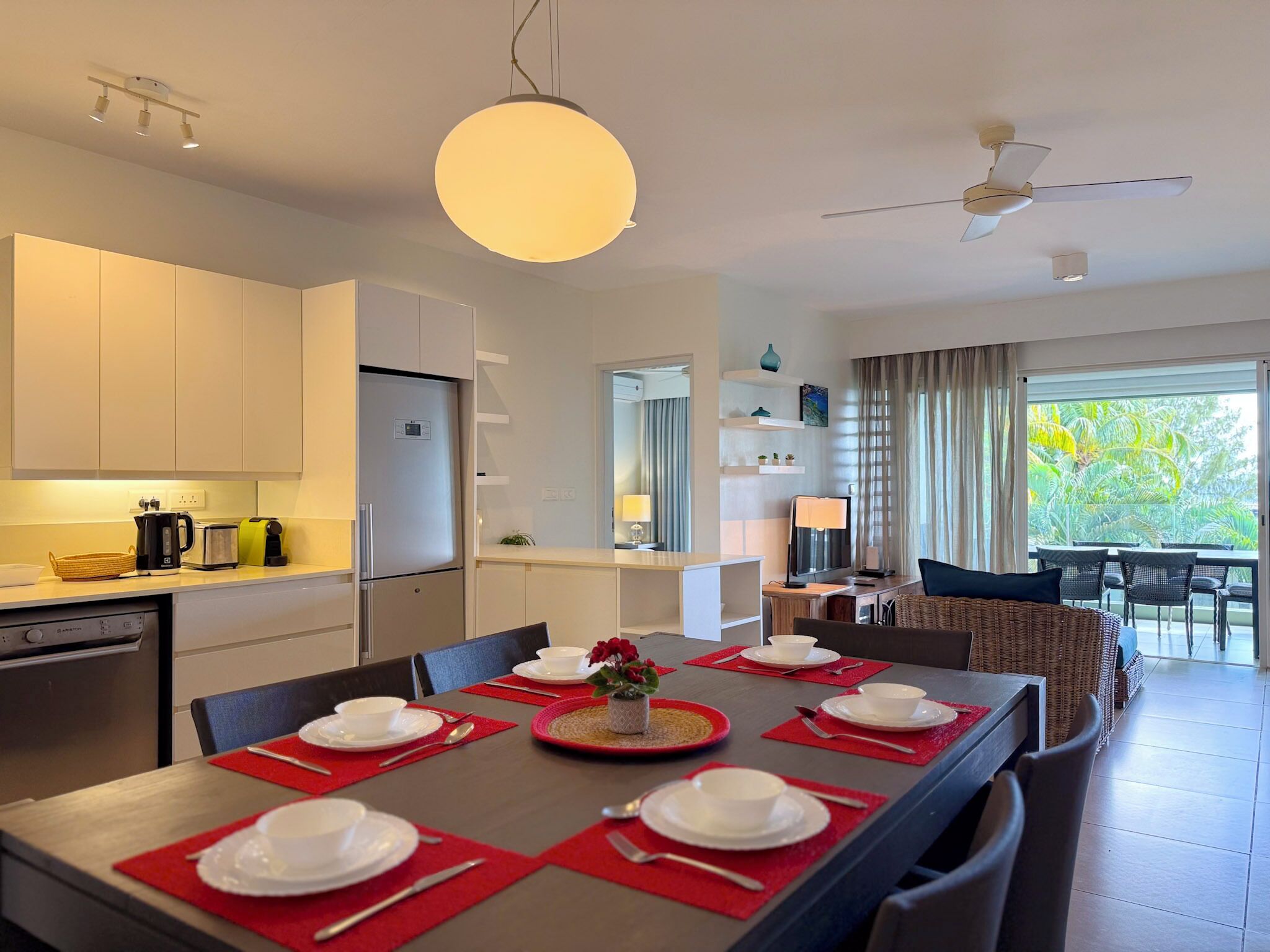 A modern kitchen with white cabinets, a built-in refrigerator, and a dining area with a table set for four.