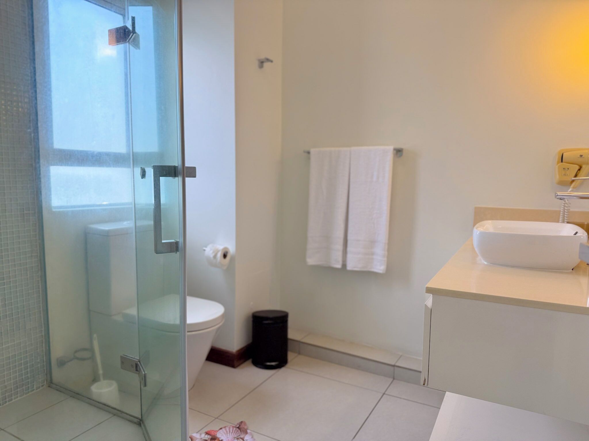 A modern bathroom with a glass shower enclosure, a toilet, a sink, and a towel rack.