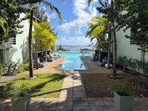 A pool area with lounge chairs and a view of the ocean. - PLAGE BLEUE BEACHFRONT APARTMENTS BY LOV (Pointe Aux Piments)