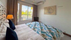Un dormitorio con cama, ventilador de techo, ventana con cortinas y aire acondicionado de pared.