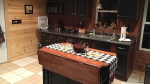 Una cocina con paredes de madera, mantel a cuadros y un lavabo.