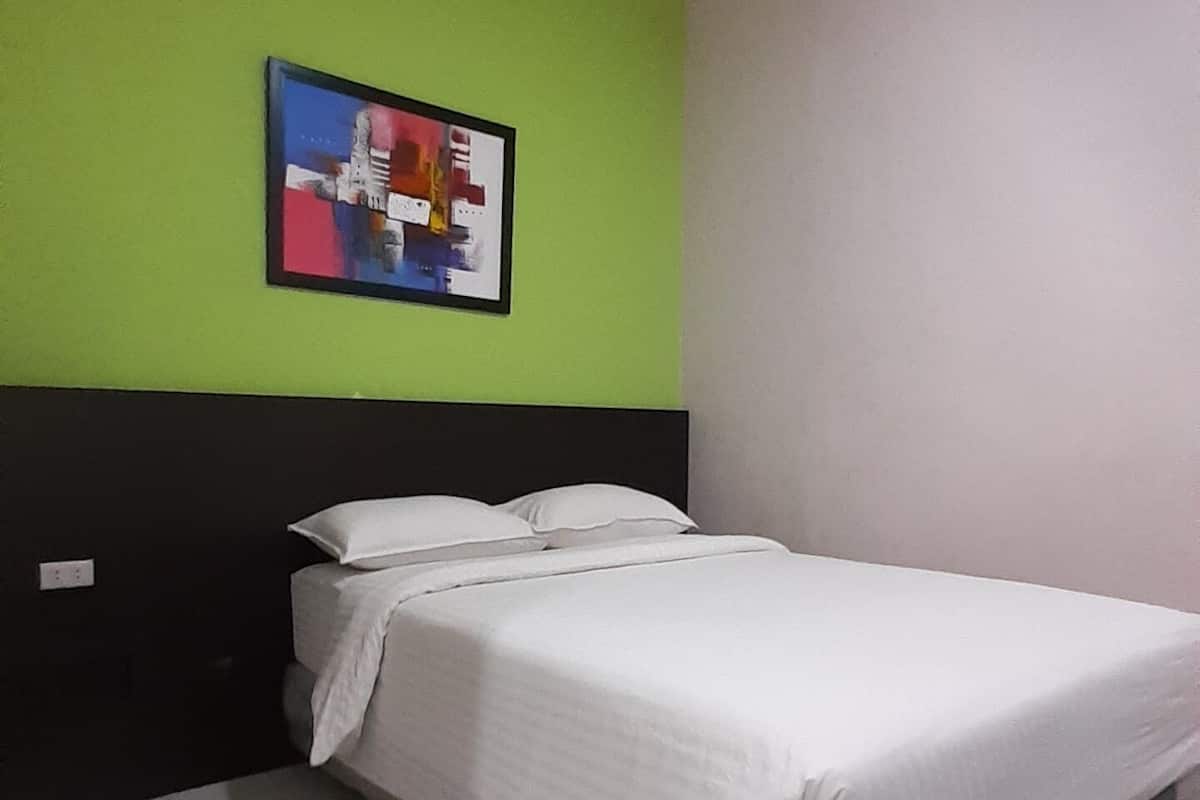 A single bed with white bedding in a room with green and white walls.