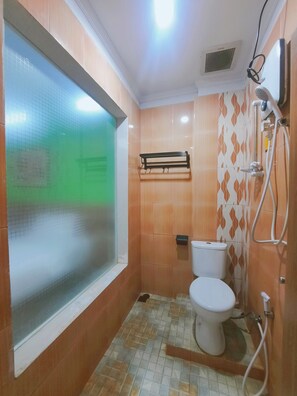 Un baño pequeño con inodoro, ducha y ventana.