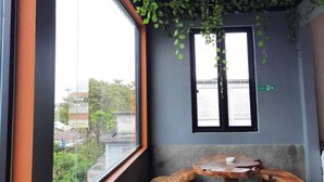 A room with a large window, a wooden bench, and hanging greenery. - Rahat Icon Hotel (Tanjung Pandan)