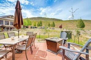 Une terrasse extérieure avec une table et des chaises, un barbecue et une vue sur un paysage vallonné.