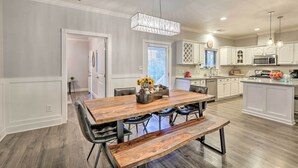 A modern kitchen with white cabinets, a central island, and a dining area with a wooden table and benches. - Pet-Friendly Flagstaff Escape w/ Fenced-In Yard! (Flagstaff)