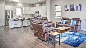 Un salon spacieux avec un fauteuil inclinable en cuir, une table basse et un tapis bleu.