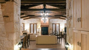 Un intérieur rustique avec des murs en pierre, des poutres en bois, une cheminée et un canapé dans un salon chaleureux.