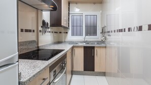 Une cuisine moderne dotée d’une cuisinière, d’un four et d’un évier encastrés, de meubles de rangement en bois et d’une fenêtre avec du verre dépoli.