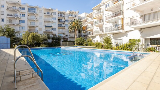 Une piscine équipée d’un escalier en métal, entourée d’immeubles résidentiels à plusieurs étages.