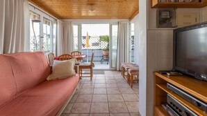 A living room with a wooden ceiling, a pink sofa, a television, and a balcony with a table and chairs. - Cozy Apartment with Private Terrace, Roof Top and Air Conditioning (Nerja)