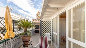 A balcony with a table, chairs, a potted plant, and a yellow umbrella. - Cozy Apartment with Private Terrace, Roof Top and Air Conditioning (Nerja)
