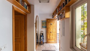 A hallway with wooden doors, a mirror, a coat rack, and bookshelves. - Cozy Apartment with Private Terrace, Roof Top and Air Conditioning (Nerja)