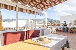 A terrace with a table, chairs, and a view of mountains. - Cozy Apartment with Private Terrace, Roof Top and Air Conditioning (Nerja)
