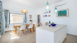 Een moderne keuken met een centraal eiland, hanglampen en uitzicht door het raam.