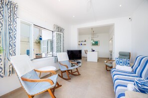 Ein modernes Wohnzimmer mit Fernseher, Sitzgelegenheiten und Blick ins Freie.