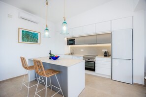 Eine moderne Küche mit Kochinsel, weißen Schränken und einem Edelstahlkühlschrank.