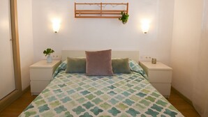Una camera da letto con un letto, due comodini, una mensola a muro con una pianta e due applique.