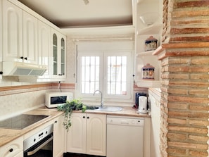A compact kitchen with white cabinetry, a built-in microwave, a gas stove, and a dishwasher.