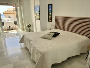 A hotel room with a bed, a view through a sliding door, and a painting on the wall. - Great Townhouse 400m from the Beach with Sea View, Wi-Fi and Air Conditioning (Benalmádena)