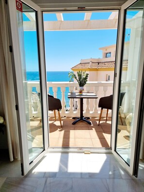 A balcony with a table and chairs, a potted plant, and a view of the sea. - Great Townhouse 400m from the Beach with Sea View, Wi-Fi and Air Conditioning (Benalmádena)