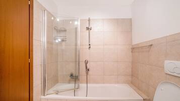 Un baño con ducha de vidrio, una bañera y un inodoro.