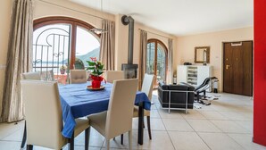 Un área de comedor con una mesa dispuesta para dos personas, un sofá, una chimenea y vistas al exterior.