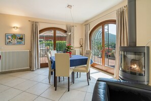 A dining area with a table and chairs, a fireplace, and large windows with curtains.