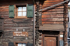 Un chalet rustique en rondins de bois, avec une enseigne indiquant « Chalet Maffin », une porte en bois et une boîte aux lettres.
