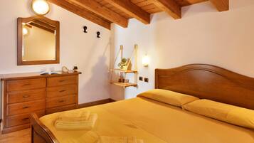 A bedroom with a wooden headboard, a bedside table, a mirror, and a wall-mounted shelf with a plant.