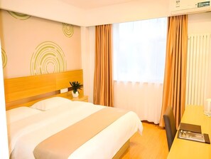 A hotel room with a bed, a bedside table with a plant, a desk with a chair, and a window with curtains. - Greentree Alliance Beijing Shunyi District Xiaoying Hotel (Shunyi)