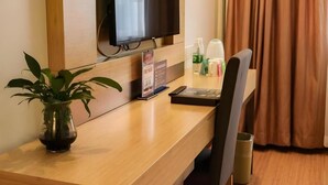 A hotel room with a wooden desk, a television mounted on the wall, a potted plant, and a window with curtains. - Greentree Alliance Beijing Shunyi District Xiaoying Hotel (Shunyi)