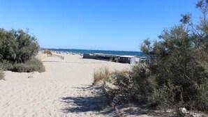 A sandy beach path leading to a building with a view of the sea. - Pretty T2 garden level at Couchant 200m from the beach in a residence with swimming pool (La Grande-Motte)