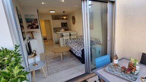 A modern apartment with a balcony, a dining area, and a kitchen. - Pretty T2 garden level at Couchant 200m from the beach in a residence with swimming pool (La Grande-Motte)
