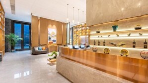 A modern reception area with a marble counter, shelves with decorative items, and a seating area with a sofa and a coffee table. - Greentree Eastern Tongling City Beijing West Road Big Dipper City Hotel (Tongling)