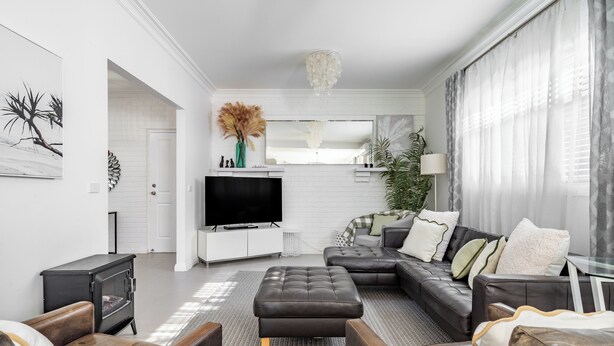 Ein modernes Wohnzimmer mit einem Ecksofa, einem Flachbildfernseher und einem Kamin.