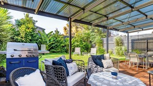 Eine Terrasse im Freien mit Grill, Korbmöbeln und einem Tisch mit Spitze.