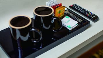Un plateau avec deux tasses noires, une télécommande et quelques en-cas.