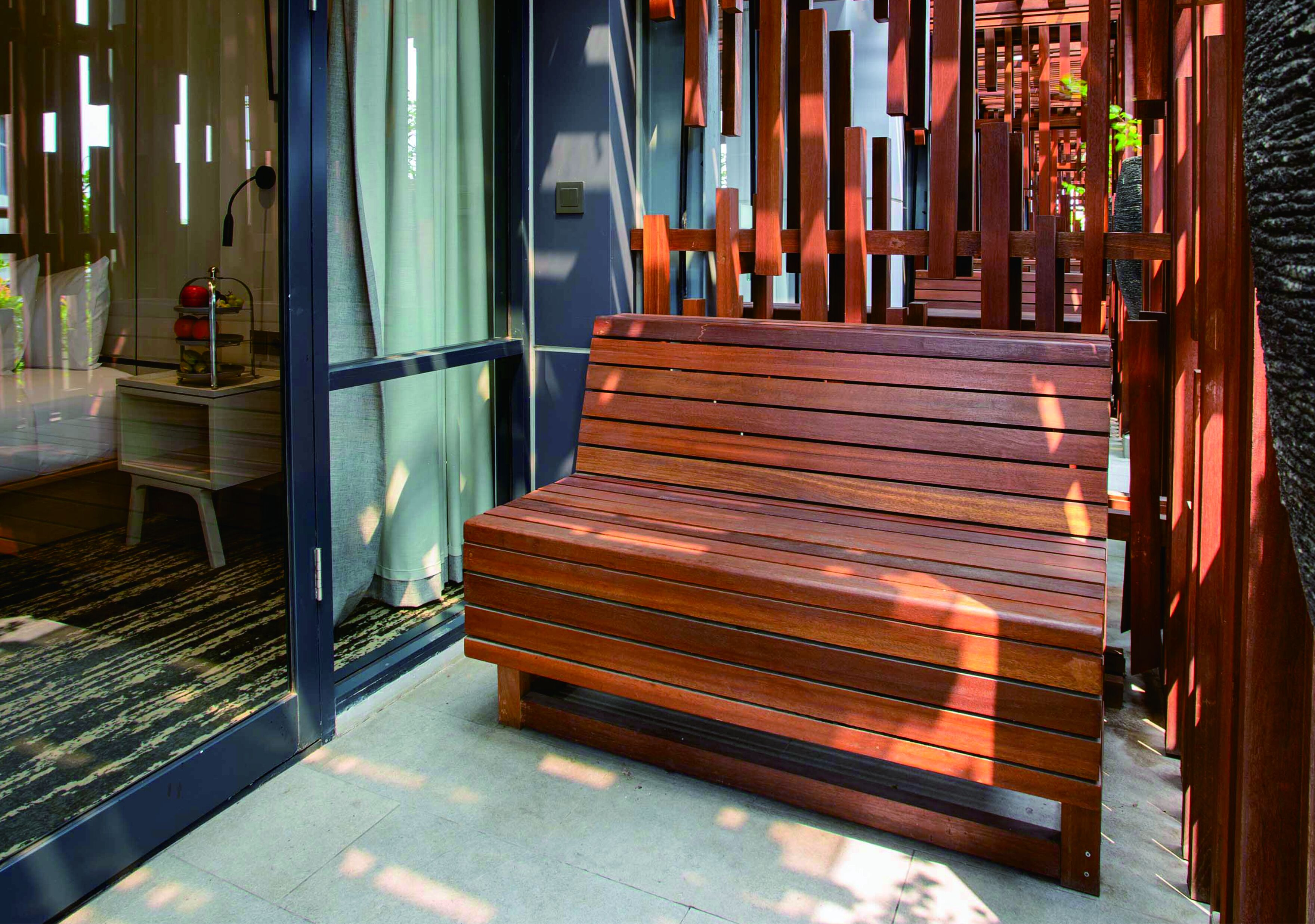 A wooden bench in a modern interior space with a glass door and a metal railing.