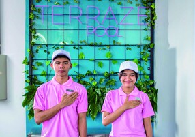 Duas pessoas de camisas cor-de-rosa em frente a uma parede azul com o texto "TERRAZE POOL".