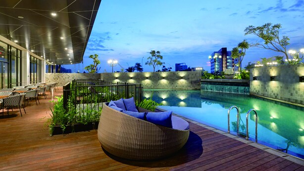 A rooftop pool area with a lounge chair, outdoor seating, and a view of the city skyline. - THE 1O1 Jakarta Airport CBC (Tangerang)