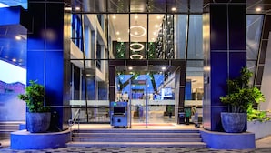 A modern building entrance with glass doors, a digital display, and a vending machine. - THE 1O1 Jakarta Airport CBC (Tangerang)