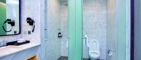 Een moderne badkamer met een marmeren wand, een glazen douchecabine, een wastafel met spiegel en een toilet.