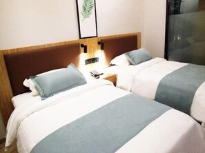 Een hotelkamer met twee bedden, een nachtkastje en een ingelijst foto aan de muur.