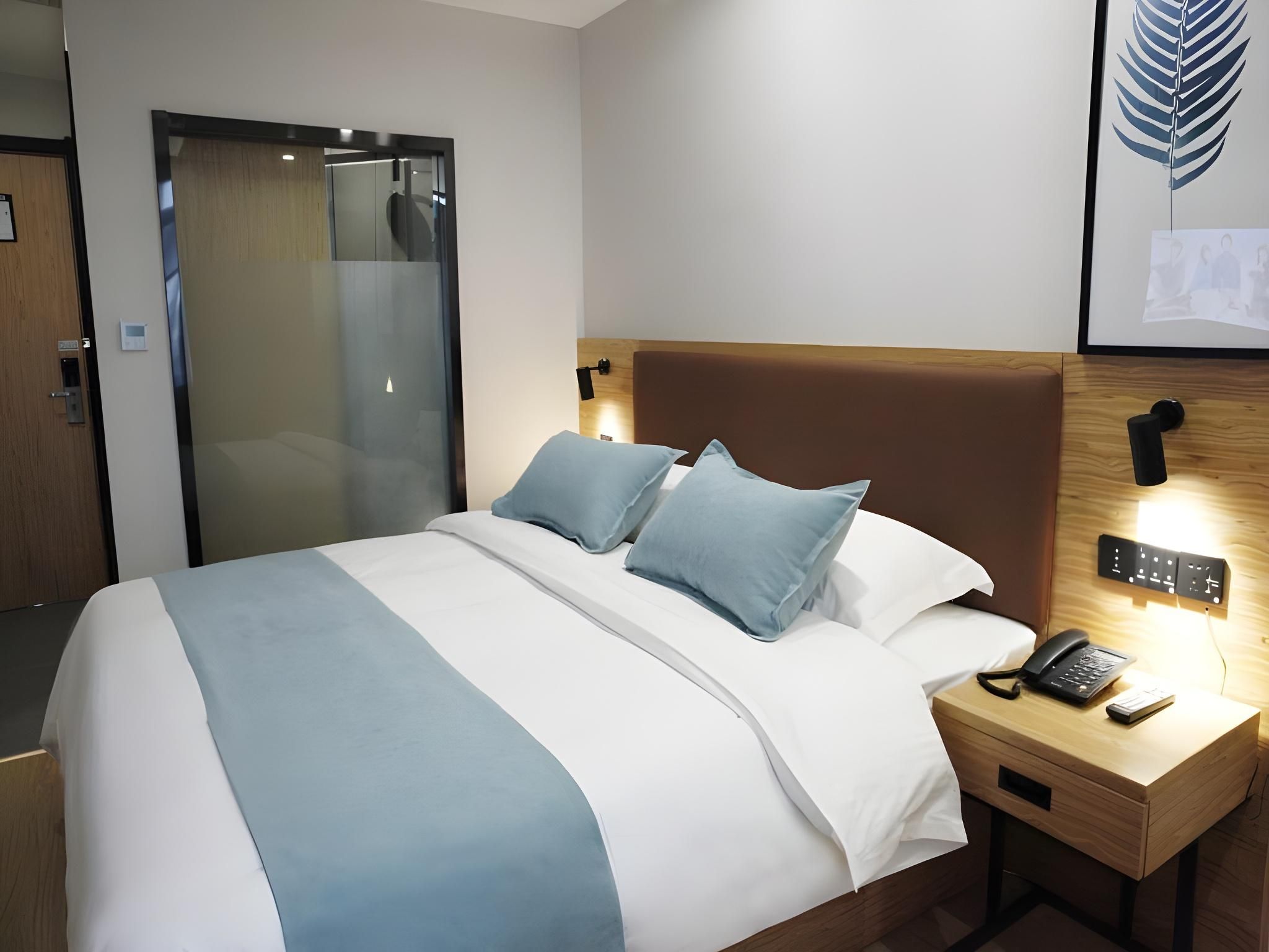 Ein Hotelzimmer mit Bett, Nachttisch und einem an der Wand montierten Telefon.