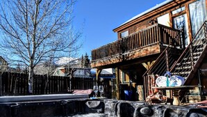 Un edificio rústico de madera con un balcón, una valla de madera y un suelo cubierto de nieve.