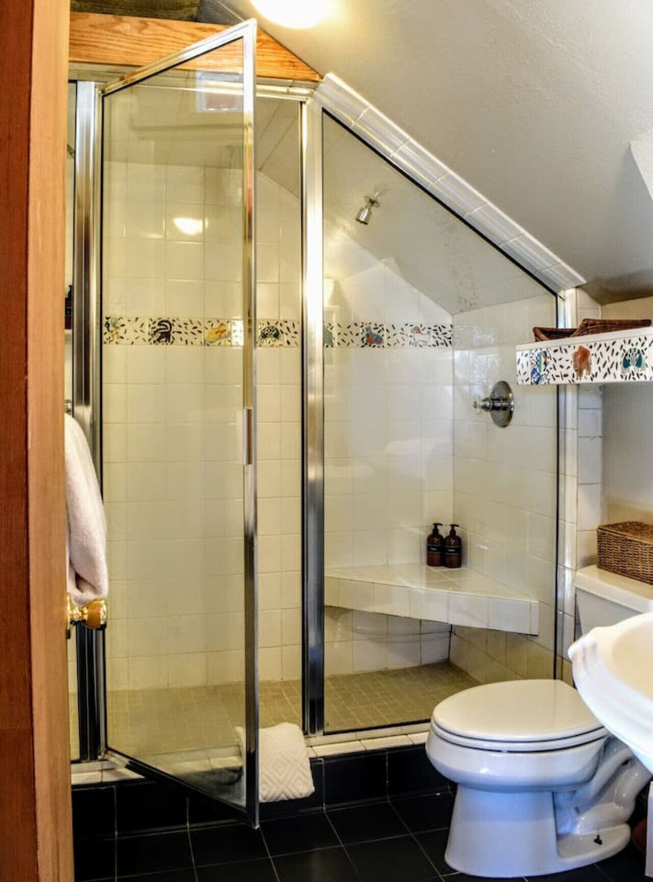 A bathroom with a glass shower enclosure, a toilet, and a sink.