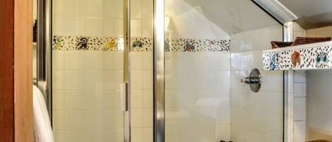 A bathroom with a glass shower enclosure, a toilet, and a sink.