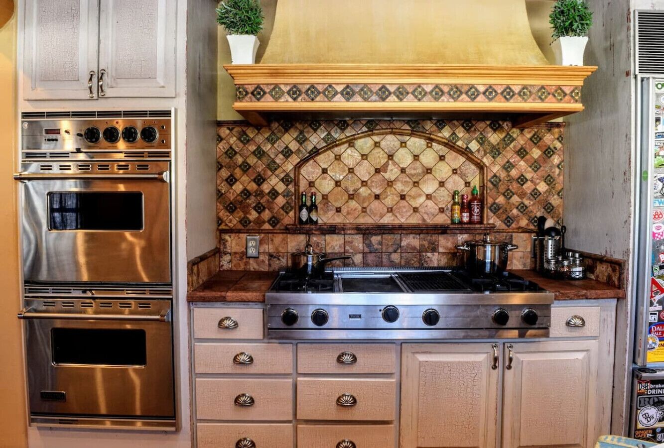 Una cocina con electrodomésticos de acero inoxidable, un salpicadero con diseño y armarios de madera.