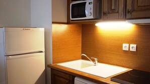 Eine kleine Küche mit Kühlschrank, Mikrowelle, Spüle, Geschirrspüler und Holzschränken.